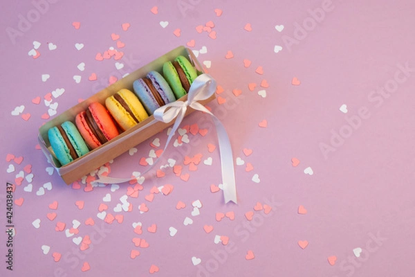Fototapeta Multicolored macarons in a paper box and multicolored sweets on a romantic background.