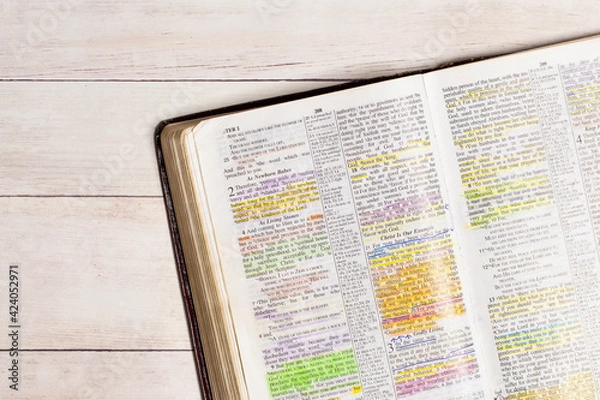 Fototapeta Used and Highlighted Bible Open on a White Wood Table