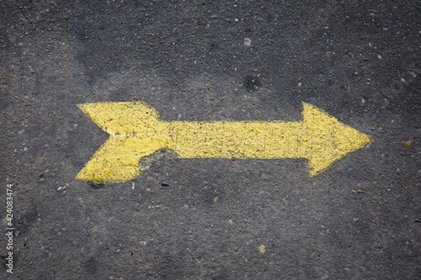 Fototapeta Yellow arrow painted on concrete sidewalk pointing right