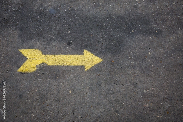 Fototapeta Yellow arrow painted on concrete sidewalk pointing right