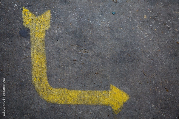 Fototapeta Yellow curved arrow painted on concrete sidewalk pointing right
