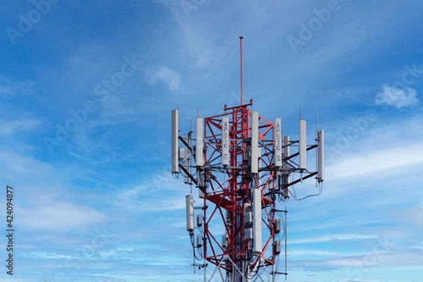 Fototapeta Telecommunication tower of 4G and 5G cellular. Macro Base Station. 5G radio network telecommunication equipment with radio modules and smart antennas mounted on a metal against blue sky background.