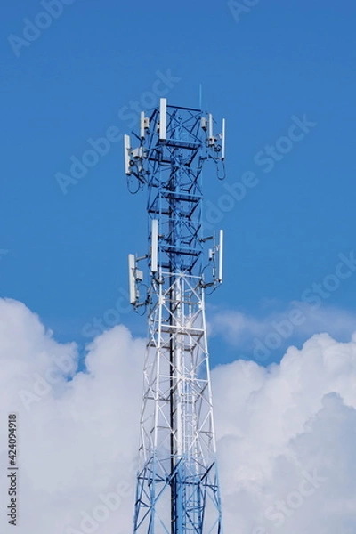 Fototapeta Telecommunication tower of 4G and 5G cellular. Macro Base Station. 5G radio network telecommunication equipment with radio modules and smart antennas mounted on a metal against cloulds sky background.