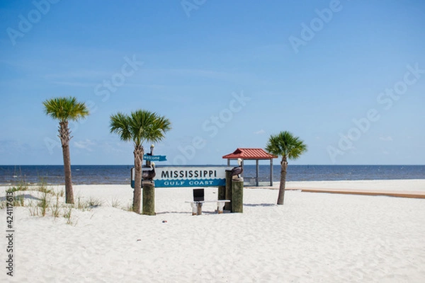 Fototapeta Beautiful summer landscape by the ocean with white sand and clear blue skies, palm trees and a gazebo on a summer sunny day.Ken Combs Pier, Gulfport, Mississippi, USA - 7-4-2019