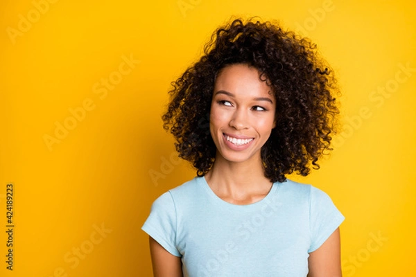 Fototapeta Photo portrait of dreamy afro american woman looking at blank space isolated on vivid yellow colored background