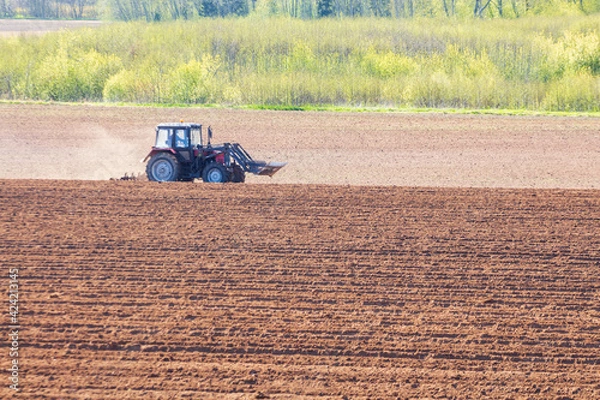 Obraz tractor plows the field on a sunny spring day