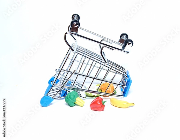 Obraz An upturned blue grocery cart with groceries. Isolated on a white background. The concept of sales and purchases.