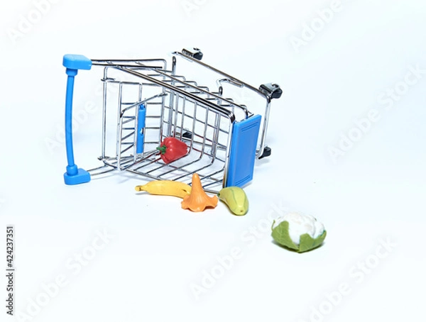 Obraz An upturned blue grocery cart with groceries. Isolated on a white background. The concept of sales and purchases.