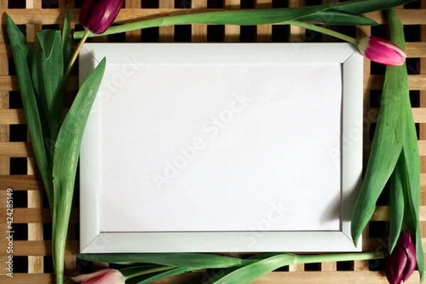 Obraz Poster with copy space in warm shades . Mockup of a wooden frame with tulips around. White, minimalism. copy space. Mock up design.