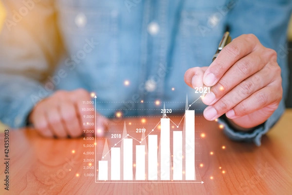 Obraz Businessman plans business growth in 2021. Concepts of finance, marketing, Sales increase and Business Growth Planning with technology. Analysis using graphs