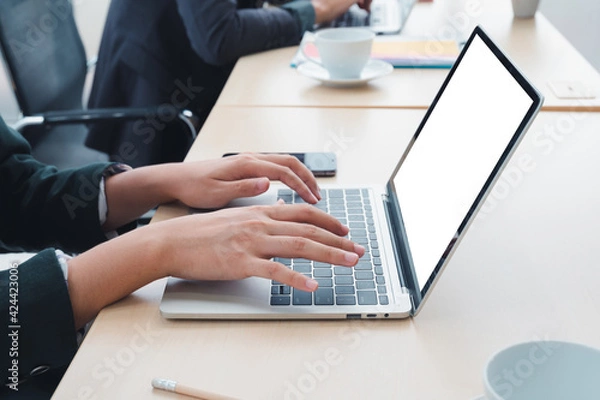 Fototapeta Businessman working at a home office uses a close-up keyboard, a man sitting on a wooden table and using a contemporary laptop by the window. Concept of close-up of a hand printed on a laptop.