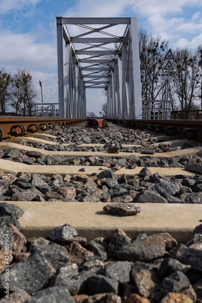 Fototapeta A close-up on rails and a railway bridge. Perspective photo taken on a sunny day.