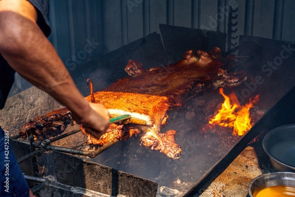 Fototapeta A whole crispy pork grilled on hot coals