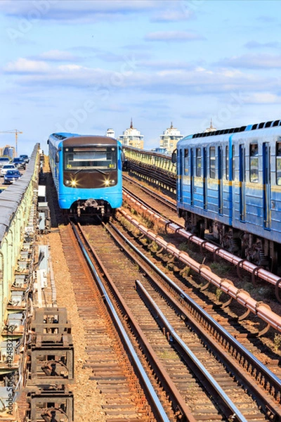 Fototapeta Two metro trains travel on rails towards each other along the Kyiv metro bridge across the Dnipro River.