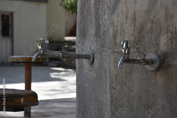 Fototapeta fountain on the wall. Closeup of brass faucet on public water fountain in urban park, Public bronze faucet fountain in old traditional style. city Istanbul