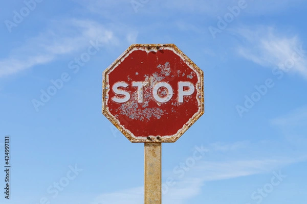 Fototapeta Rusty stop sign isolated with blue sky in the background