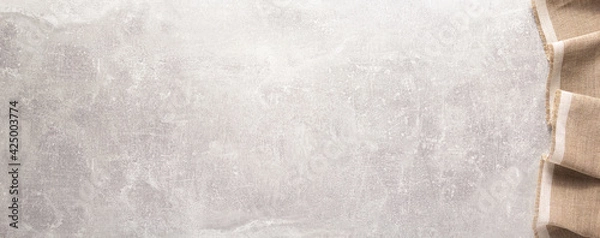 Fototapeta Folded tablecloth at stone or marble surface of table. Top view as panorama of cloth napkin texture background