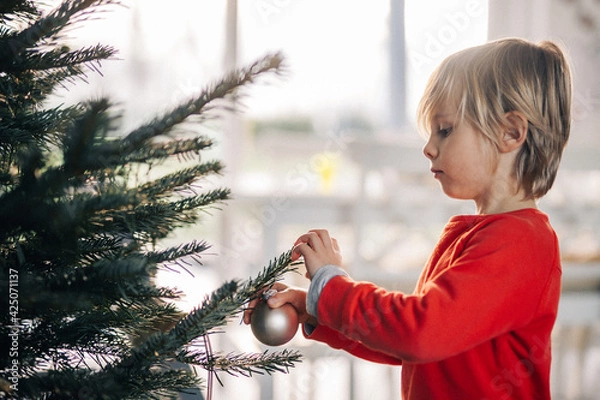 Obraz Jeune enfant décore le sapin de noël