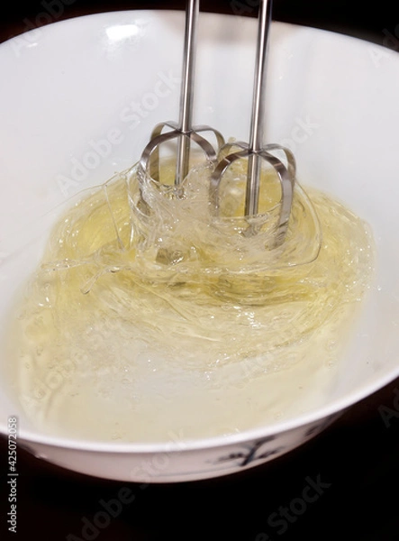 Fototapeta Making a cake: photo catching the movement of an electric whisk used to mixer eggs.