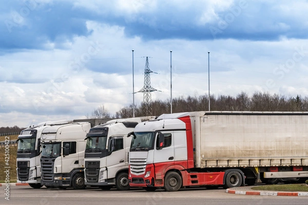 Fototapeta Trucks in a row with containers in the parking lot. Logistic and Transport concept