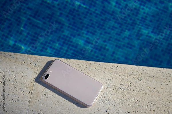 Fototapeta Clear phone case mockup in hand on the background of the swimming pool smartphone back view