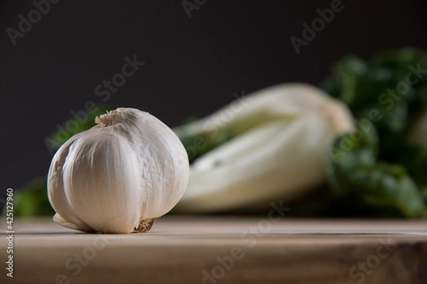 Obraz Garlic on wood cutting board with bok choy in the background