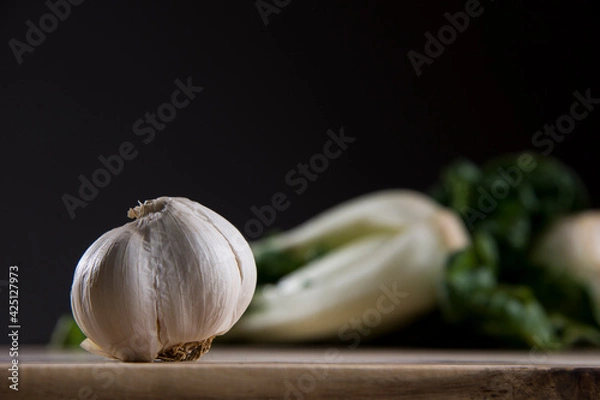 Obraz Garlic on wood cutting board with bok choy in the background