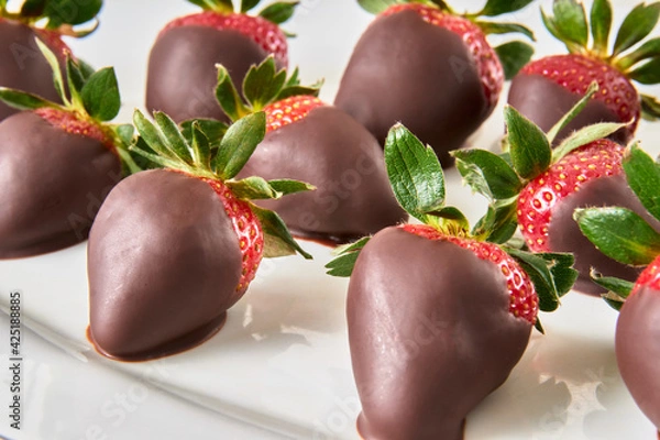 Obraz dark chocolate covered strawberries on a white plate on a marble table in close-up view. a gift for anniversaries, boyfriends or birthdays.