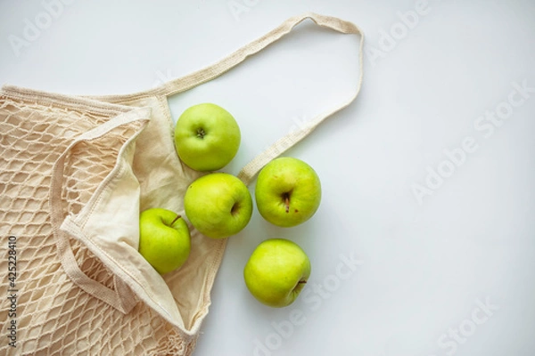 Fototapeta Zero waste shopping concept. Fresh vegetables in eco cotton bags on table in the kitchen. Apples in sustainable and ecological shopping bag. Zero waste consumption concept
