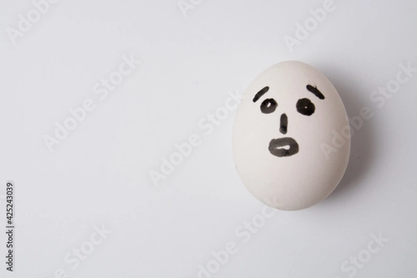 Fototapeta An egg with a surprised face, on a white background copy space.