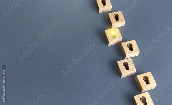 Fototapeta One glowing light bulb idea among many dark off. Concept choosing best suitable idea from presented. Innovation promising technologies. Search for talent. Developing startup. Business accelerator.