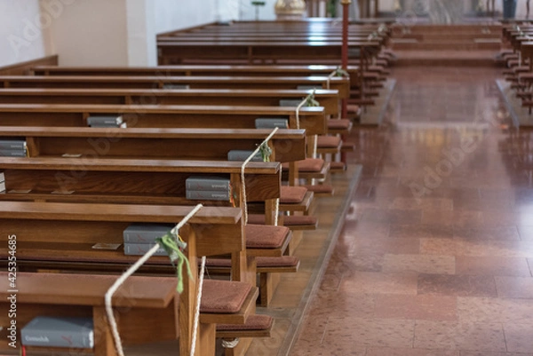 Fototapeta Leere Bänke in einer Kirche mit Abstandsbänder für Abstandsregeln