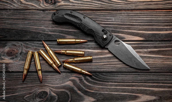Obraz Pocket folding knife and a few rifle cartridges on a wooden back