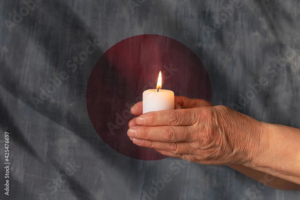 Fototapeta Hands hold a candle against the background of the flag of Japan. The concept of mourning and sadness in the country, terrorism.