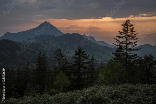 Obraz 高原の向こうで雲間から夕日が顔を出そうとしている