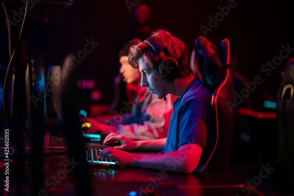 Fototapeta Professional esports players at an online game tournament. The cyber team plays computers and trains