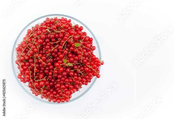 Fototapeta Large bowl of red currant with sprigs on a white background.