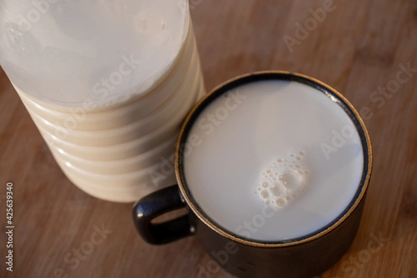 Obraz Glass of milk standing on old wooden table. Black glass with white milk. Black glass with white milk on the table