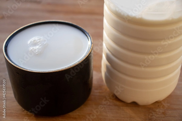 Obraz Glass of milk standing on old wooden table. Black glass with white milk. Black glass with white milk on the table