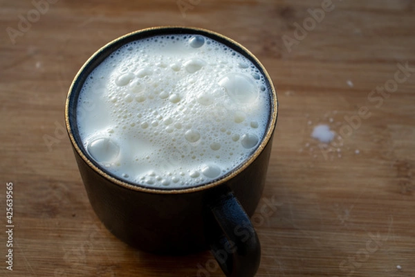 Obraz Glass of milk standing on old wooden table. Black glass with white milk. Black glass with white milk on the table