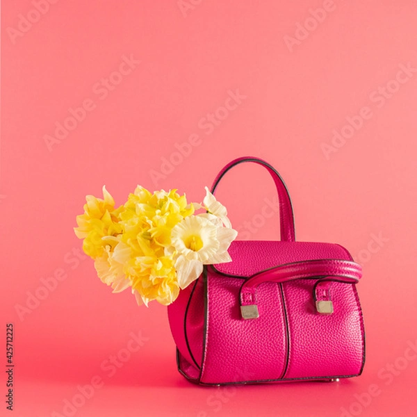 Fototapeta women small pink bag with fresh yellow narcissus on pink pastel summer background. minimal abstract art.