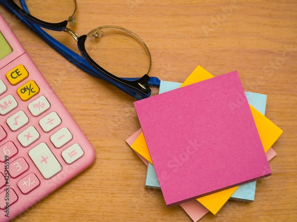 Obraz Notepads are placed on top of each other and a calculator is placed on the left side with glasses.