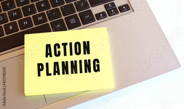 Fototapeta Notepad with the text ACTION PLANNING is on the laptop keyboard. Business concept.