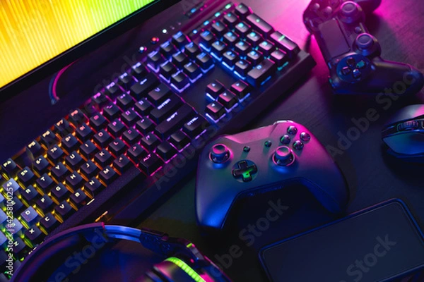 Fototapeta gamer work space concept, top view a gaming gear, mouse, keyboard, joystick, headset with rgb color on black table background.