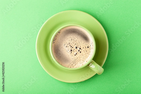 Fototapeta Hot fresh coffee with foam in the green cup on a color background