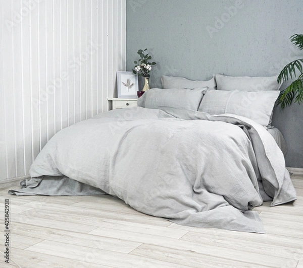 Obraz Sleeping place in the room. Pillows and duvets on the bed with 100% linen bedding. Good home textiles and quality tailoring. Background for advertising sewing production of pillowcases, duvet covers