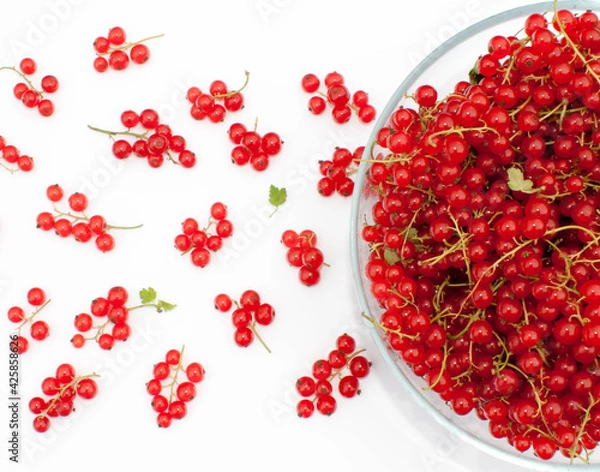 Fototapeta A large bowl of red currants with juicy bunches scattered around.