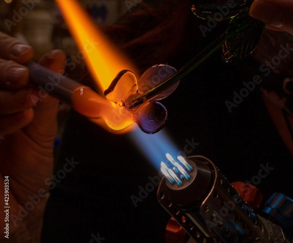 Obraz Hands of a glass artist, glass blower and their gas burner while making a decorative glass figure. Copy space