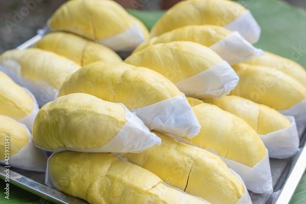 Fototapeta The golden yellow durian is placed on a stainless steel tray with a banana leaf background. Ripe durian, the king of fruits of Thailand