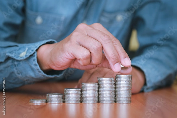 Obraz Close up part of hand Businessman is stacking coins. Saving and investment concept for the future.